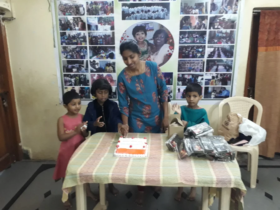 A woman and children sharing a birthday celebration around a cake